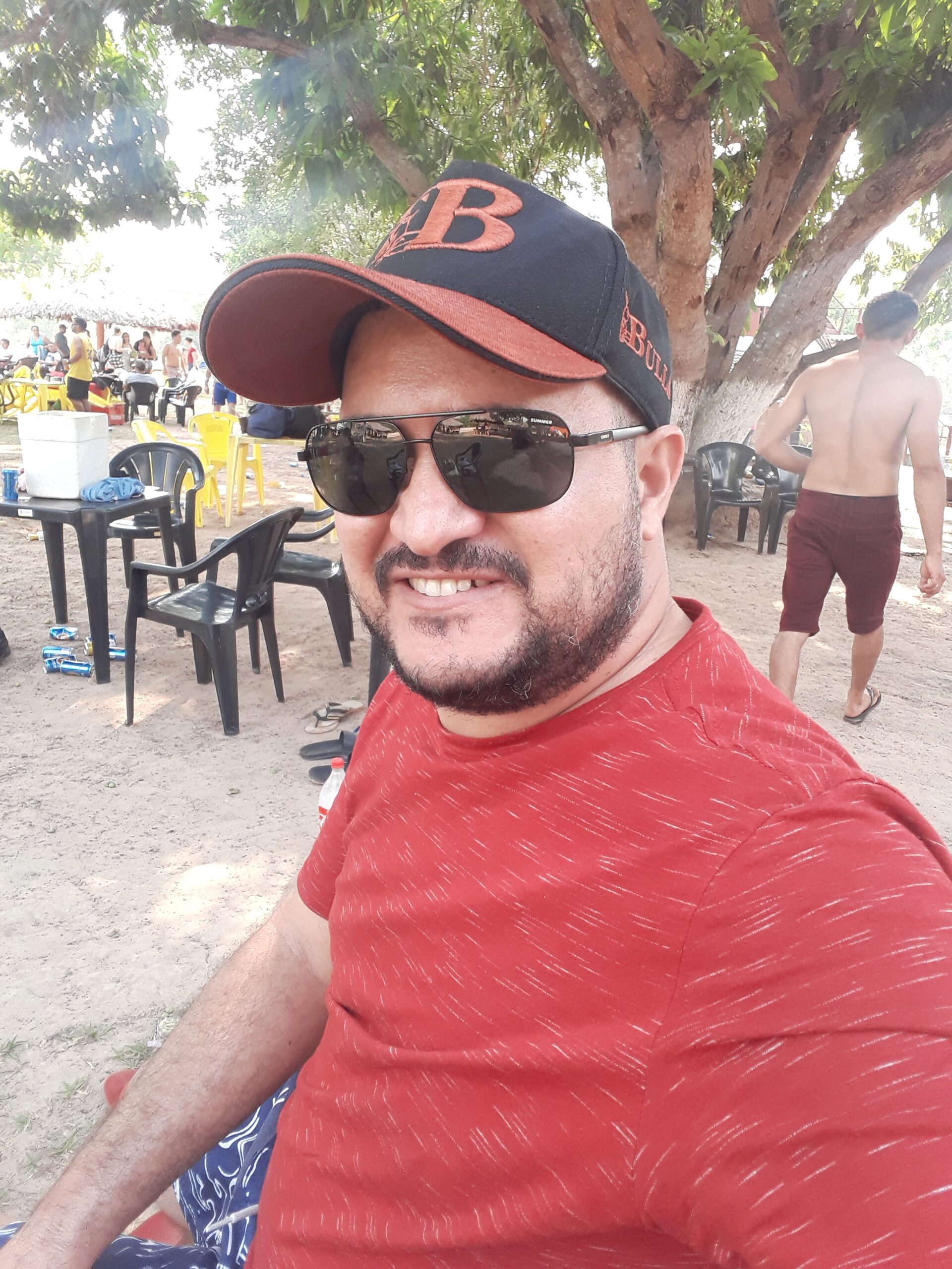 Imagem de Paulo Augusto usando boné preto, da bulls. Usa óculos escuros e a barba ainda não ficou velha